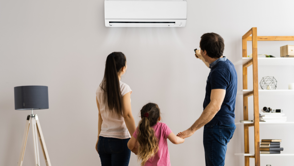 Familia en el salón regulando el aire acondicionado para mantener la temperatura ideal en el hogar de forma eficiente.