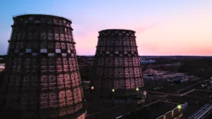Torres de refrigeración de una planta de generación eléctrica al atardecer para ilustrar la comparativa entre el mercado regulado y el libre en 2026.