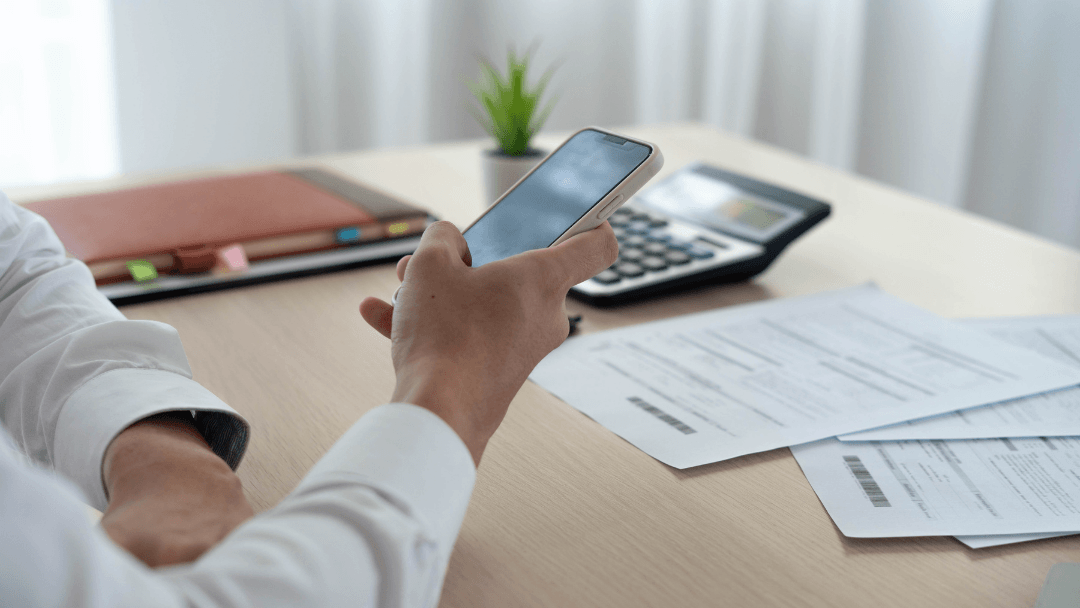 Persona revisando una factura y su móvil para contratar luz online con todos los datos preparados